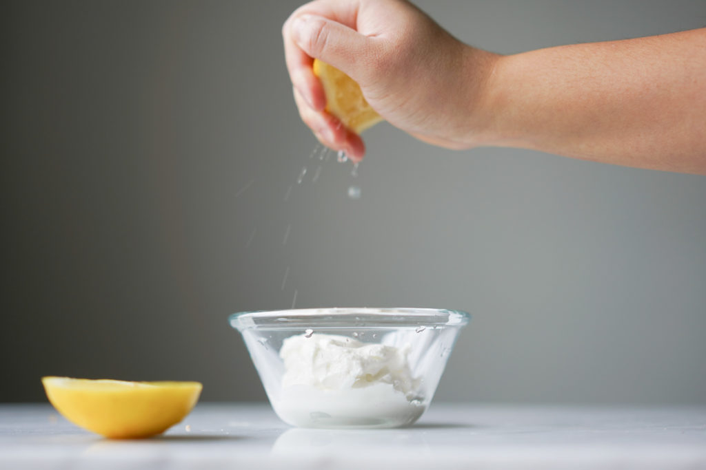 squeezing lemon juice into Greek yogurt