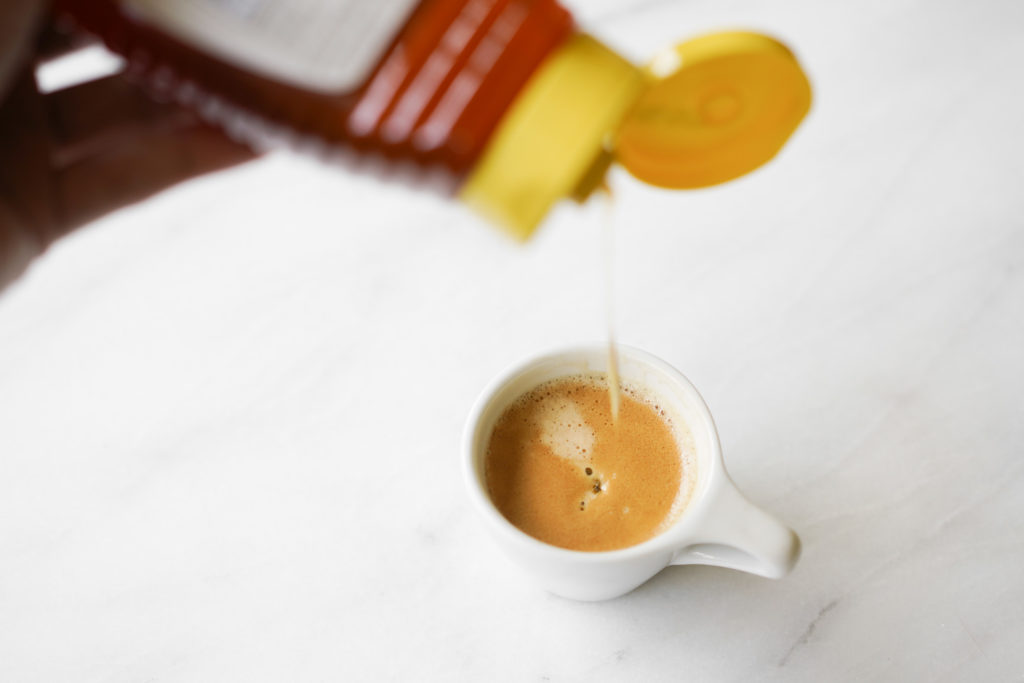 squeezing honey into a cup of espresso