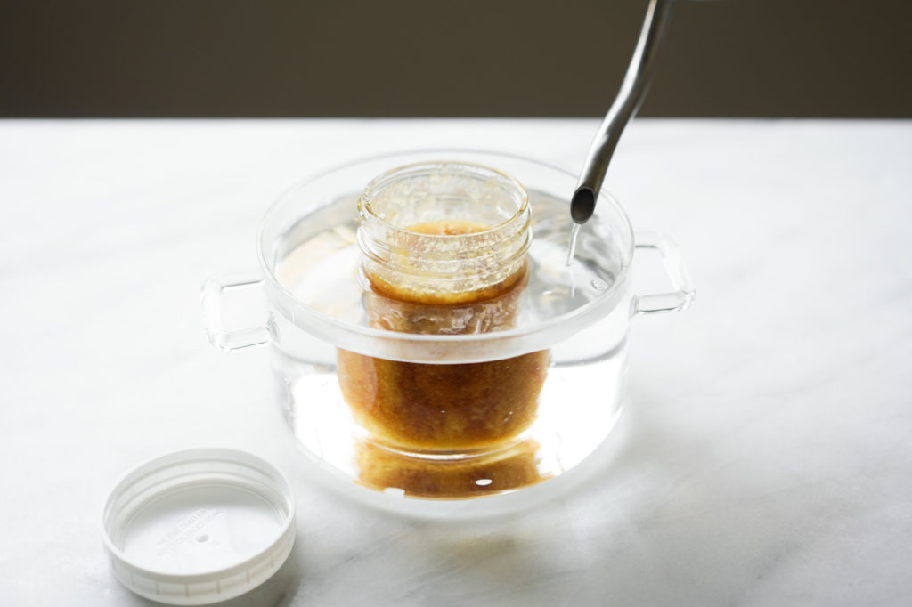 submering jar of honey in hot water