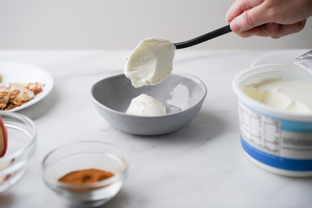 scooping Greek yogurt into a bowl