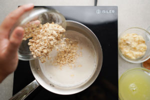 pouring in oats into almond milk