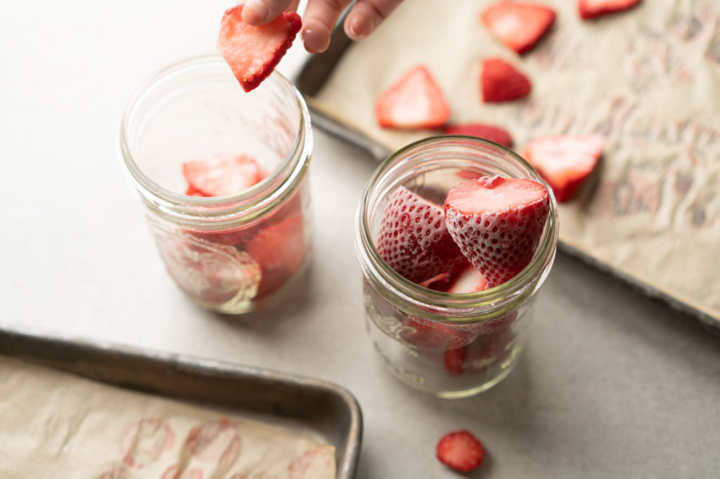 frozen whole and sliced strawberries in glass jars