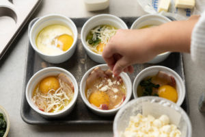 adding toppings to baked eggs