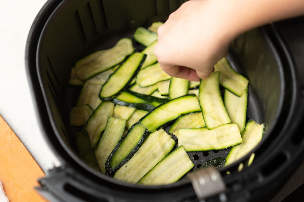 placing zucchini strips into air fryer
