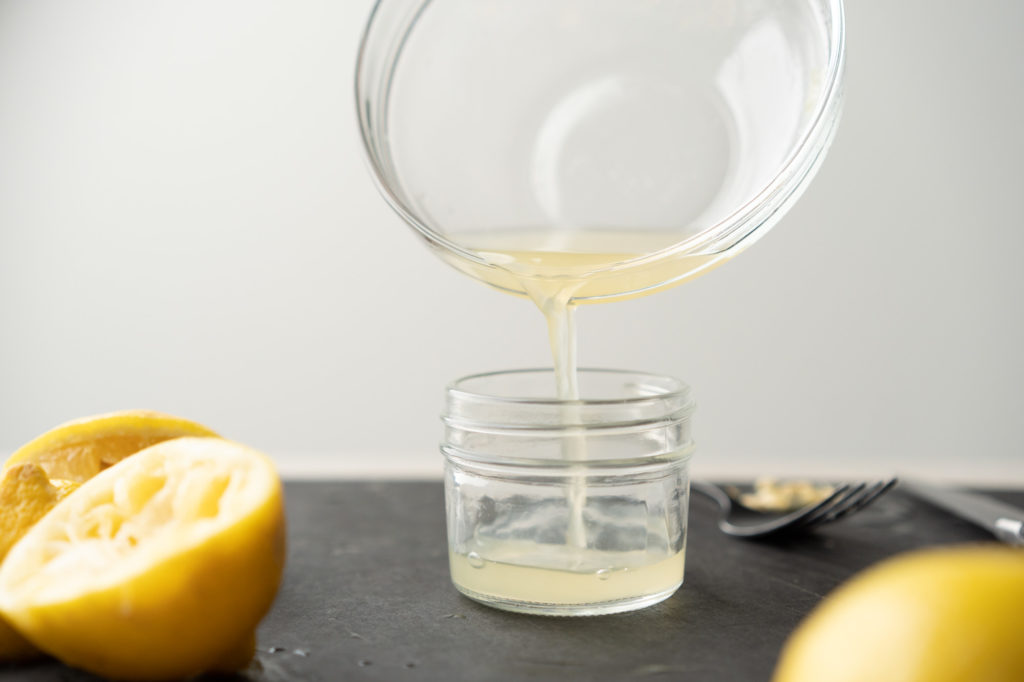 pouring lemon juice into glass jar