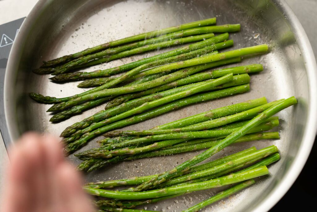 seasoning asparagus in a pan