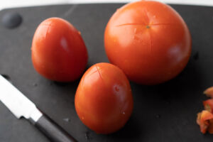 scored tomatoes on cutting board