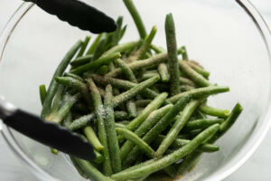 mixing seasoning with green beans