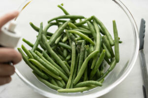 adding oil to green beans