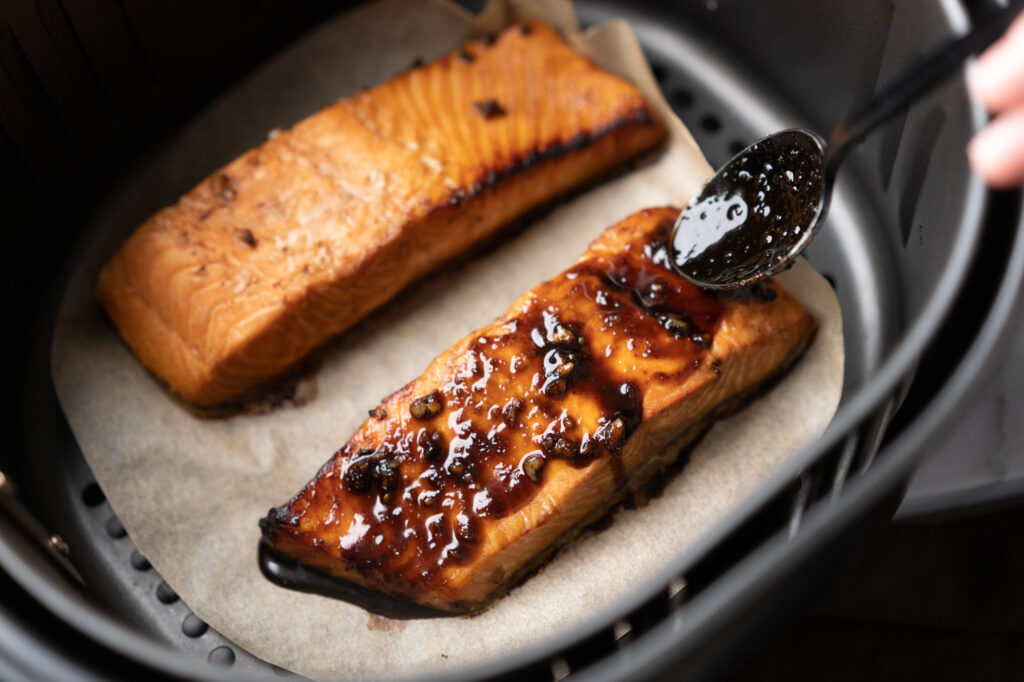 spreading teriyaki sauce on air fryer salmon