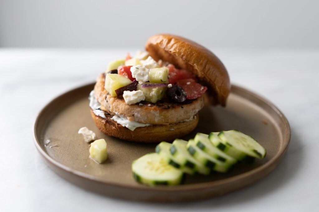 Greek inspired salmon burger with cucumber, feta, tomato, olives