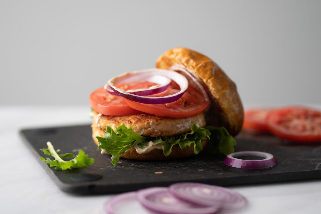 classic salmon burger with tomato, onion, remoulade